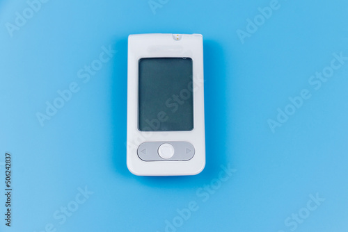 Digital glucometer on a pastel blue background. Diabetes concept