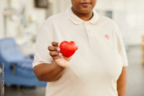 Close up of young African American woman holding red heart at blood donation center, copy space