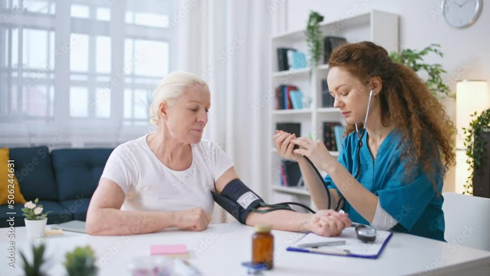 Woman therapist measuring blood pressure of senior woman, health check-up Woman therapist measuring blood pressure of senior woman, health check-up