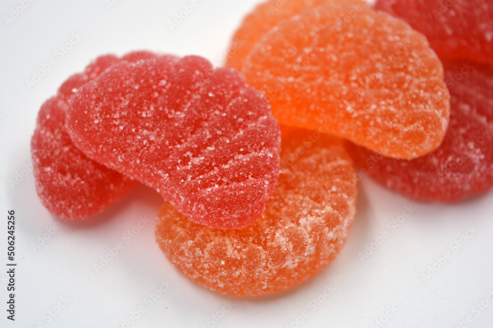 Bright red, orange jelly sweets in the form of slices of orange, mardarine, great fruit. Delicious and interesting sweets are located on a white background. Bright red, orange jelly sweets in the form of slices of orange, mardarine, great fruit. Delicious and interesting sweets are located on a white background.