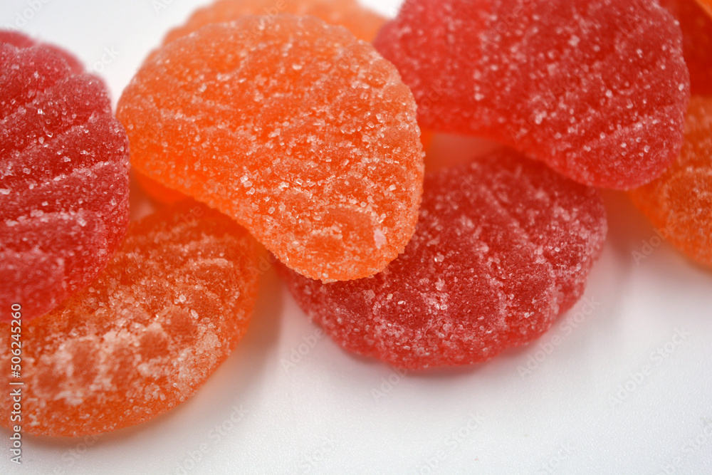 Bright red, orange jelly sweets in the form of slices of orange, mardarine, great fruit. Delicious and interesting sweets are located on a white background. Bright red, orange jelly sweets in the form of slices of orange, mardarine, great fruit. Delicious and interesting sweets are located on a white background.