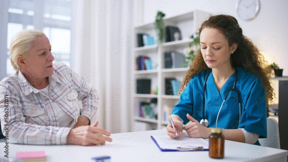 Senior woman complaining about kidney or stomach pain to female therapist Senior woman complaining about kidney or stomach pain to female therapist