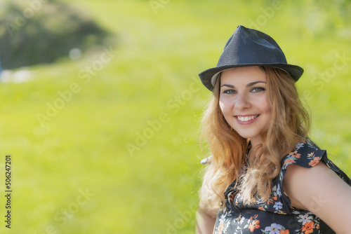 Portrait of attractive  young woman in black straw hat posing outdoors in summer day. Horizontally. 