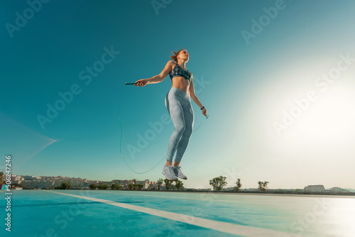 Foto Young sportswoman training jumping on an agility ladder coordinating outdoors