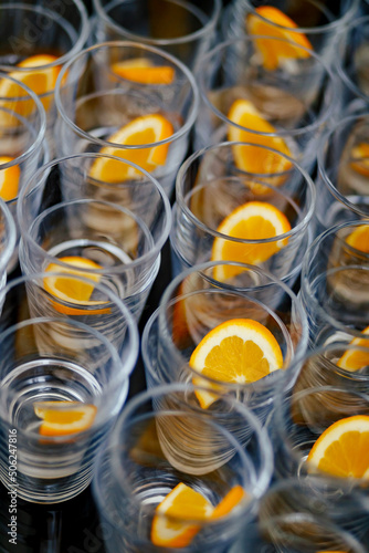 Many empty champagne glasses with orange slices decoration in the party
