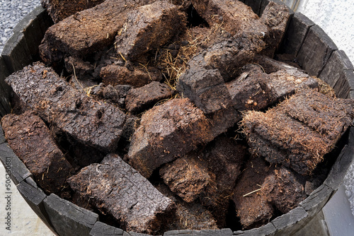 Dried lumps of peat in front of a whisky distillery. Peat is used to dry the malted barley. It gives the whisky a distinctive smoky flavour. photo