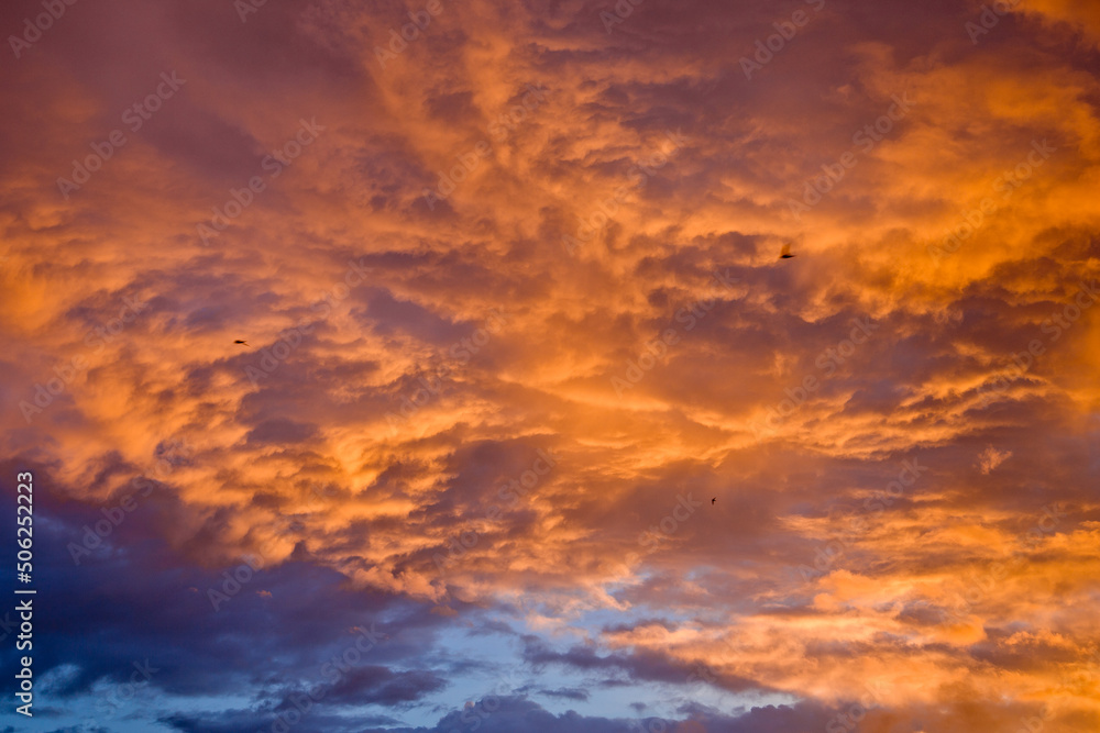 Orange sky merges with blue layered clouds