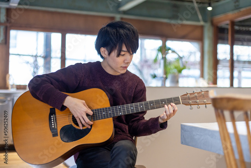 ギター演奏の練習をする20代男性