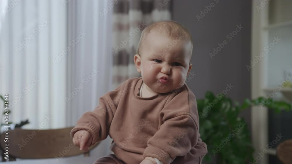 Close up portrait of an emotional baby boy infant sitting in apartment