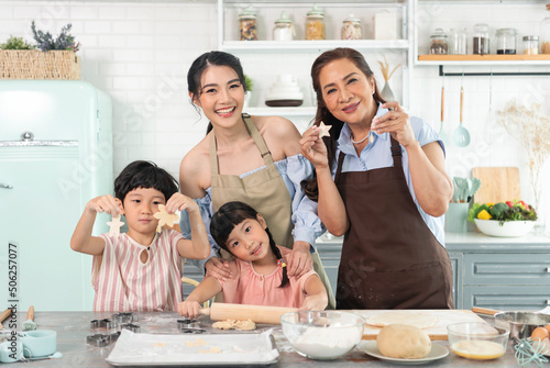 Happy Asian family making preparation dough and bake cookies in kitchen at home. Enjoy family activity together.