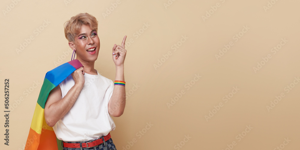 Youth asian transgender LGBT standing with finger pointing isolated over nude color background with copy space. Youth asian transgender LGBT standing with finger pointing isolated over nude color background with copy space.