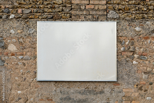 Cartello rettangolare bianco appeso a vecchio muro di pietra e mattoncino. Fotografia orizzontale. photo