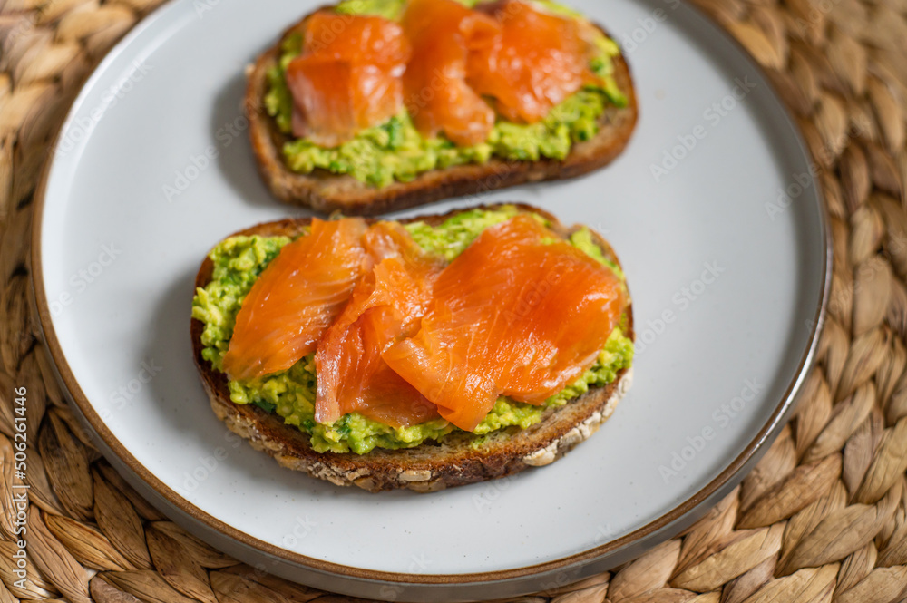Toasted bread with mashed avocado and smoked salmon on grey plate Toasted bread with mashed avocado and smoked salmon on grey plate
