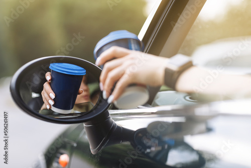 Fotografiet cropped photo of woman's hand holding blue paper cup of coffee in car