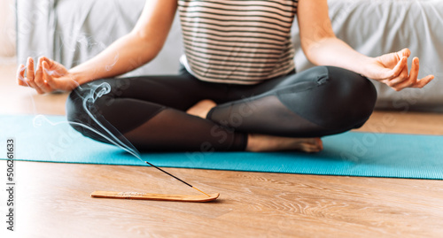 Girl does yoga on mat in front of smoldering incense.