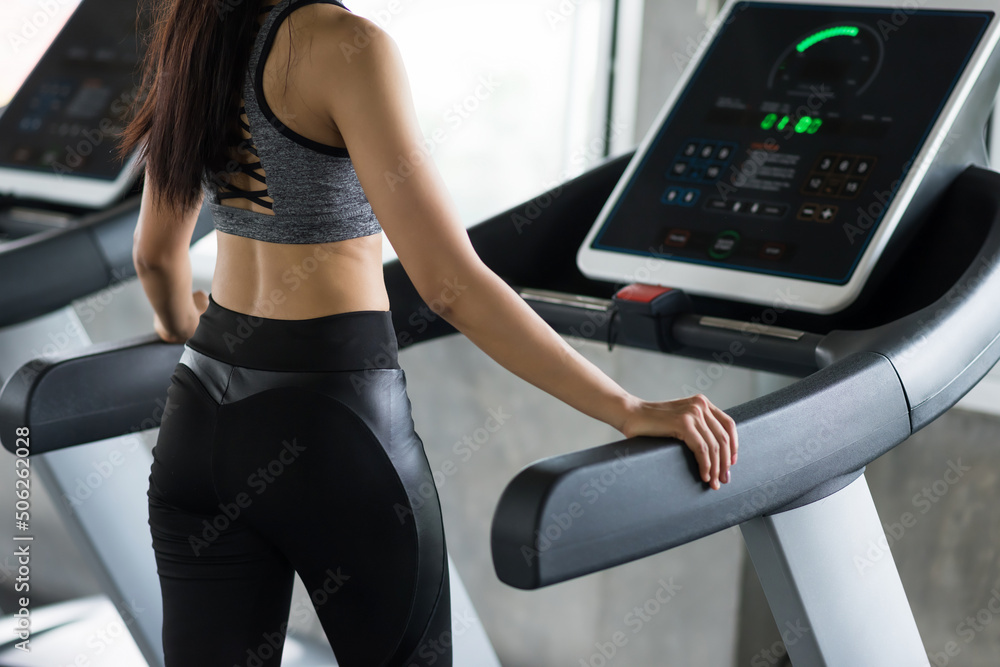 Rear of Fit Asian young woman walk and run on treadmills Rear of Fit Asian young woman walk and run on treadmills
