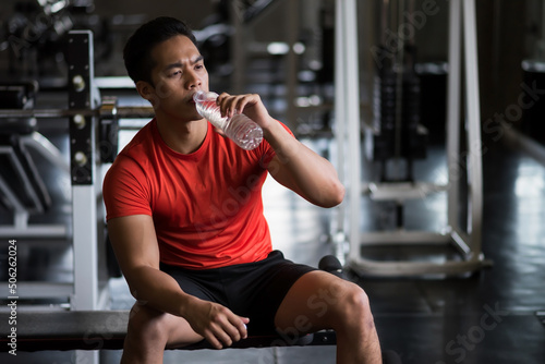 Tableau sur toile Young Asian strong muscular man drink water in fitness gym