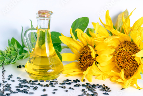 Bottle of sunflower oil and sunflower flowers with seeds on a white background