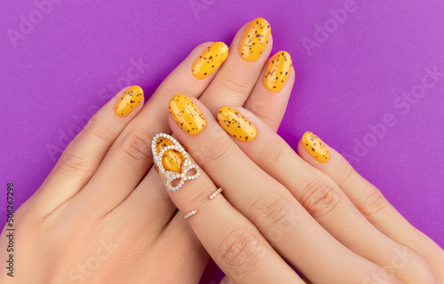 Manicured womans hands with trendy nail design on purple background
