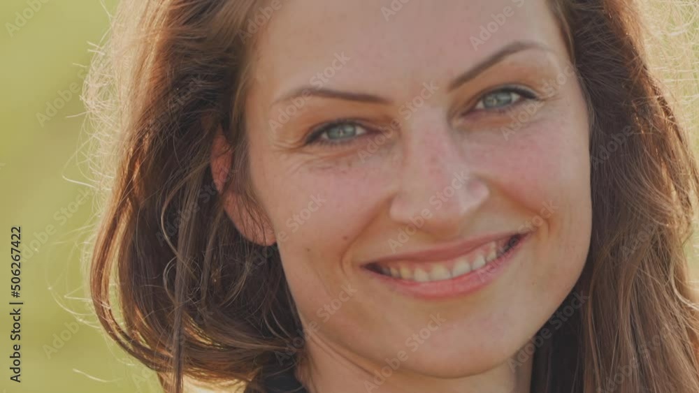 Portrait of a young charming woman with flowing hair and blue eyes. Woman looking and smiling at camera. Close-up Portrait of a young charming woman with flowing hair and blue eyes. Woman looking and smiling at camera. Close-up