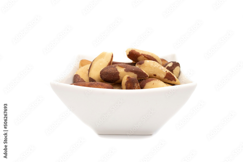 Obraz premium A white bowl with brazil nut or amazon nut, isolated on white background. Bertholletia excelsa is a tree of the Lecythidaceae family, native to South America, endemic to the Amazon.