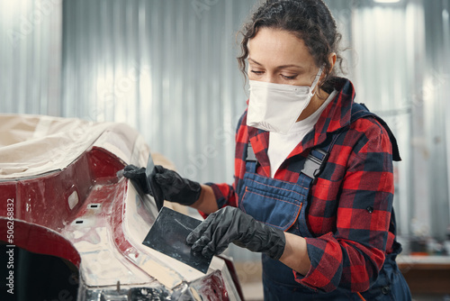 Concentrated female mechanic preparing car for repaint
