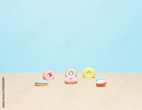 Colorful donuts in the beach sand. Summertime. Holiday or summer vacation composition.