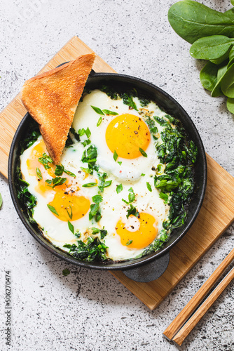 green shakshuka in a cast iron skillet. fried eggs with spinach and fried toast. healthy nutritious breakfast photo