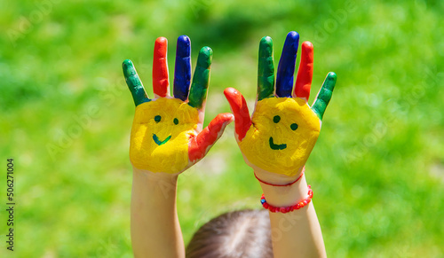 Hands of a child with a painted smile. Selective focus.