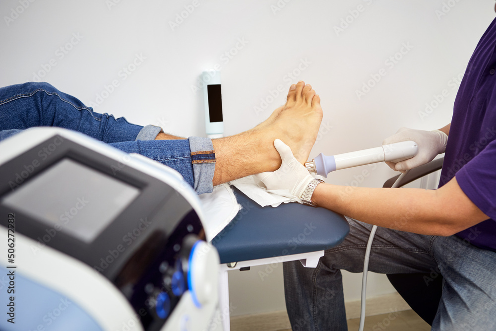 Fotka „Shock wave therapy of the heel spur. Physiotherapist doctor uses