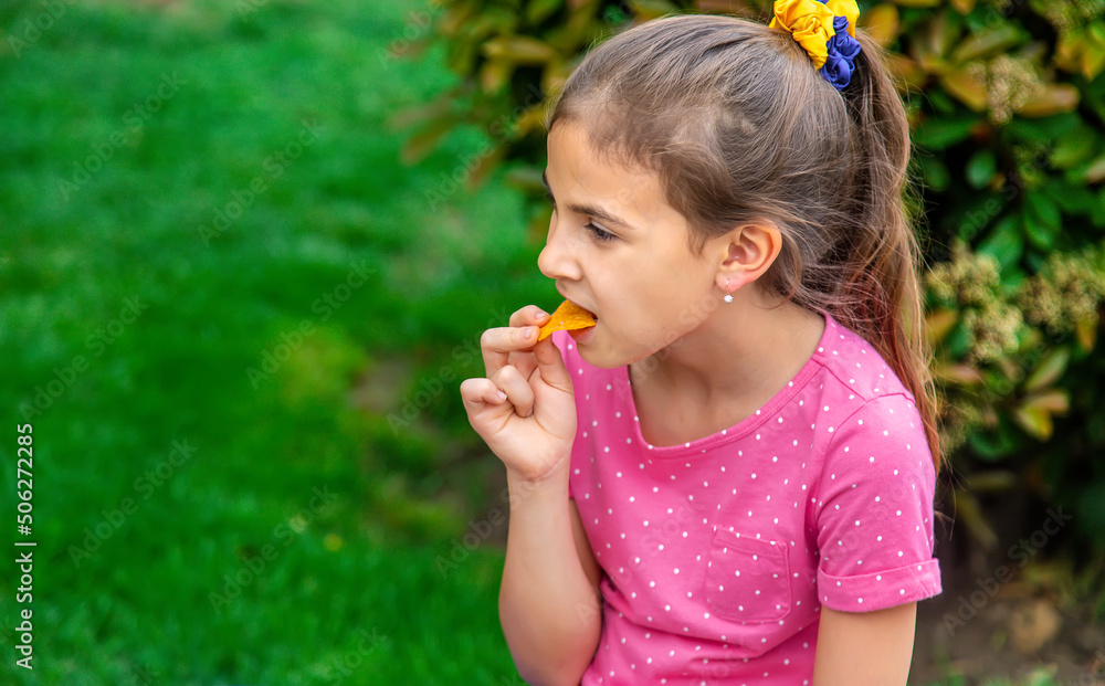 The child eats chips in the park. Selective focus. The child eats chips in the park. Selective focus.