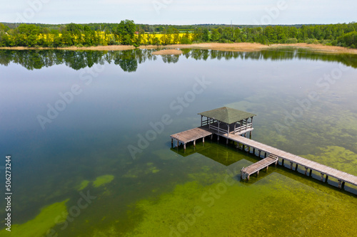 Print op canvas Summer view of clean lake at sunny day, gangway with bower above water surface,
