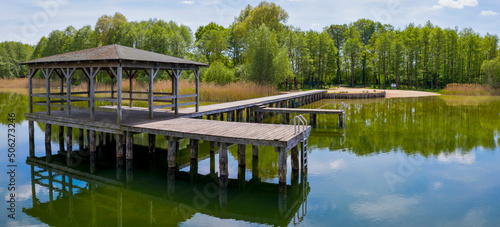 Foto Summer view of clean lake at sunny day, gangway with bower above water surface,