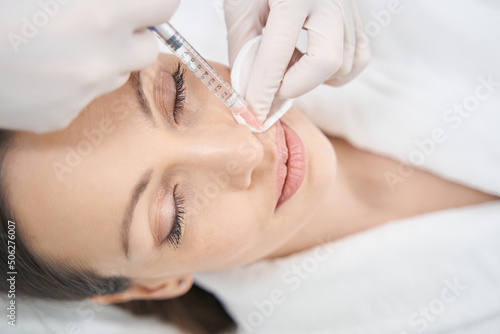 Doctor beautician doing beauty injection in woman lips