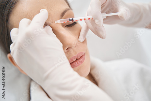 Beautician doing face lifting injection in woman forehead