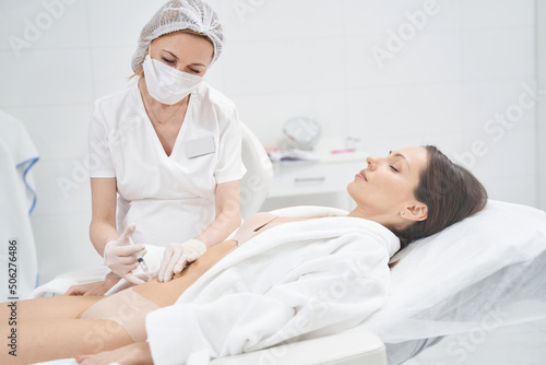 Woman receiving abdominal injection treatment in beauty salon