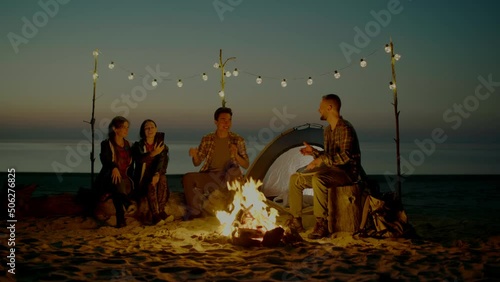 Group of young people having camp on the beach at night