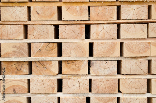 Background from lumber, pine beams. Wooden building material, background, texture. Wooden beam warehouse. Packed lumber, pine beams, background, texture. Lumber production.