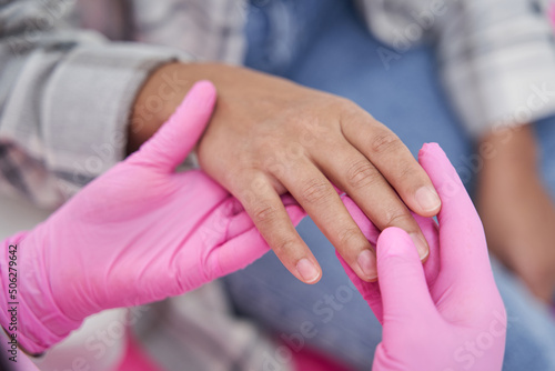 Doctor in pink sterile gloves is holding hand of patient