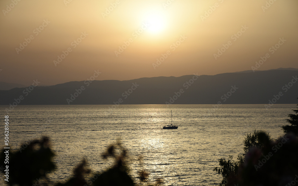 Sunset over lake. The lake view below and the soft rays of sunlight hitting the water surface on a clear day giving a feeling of peaceful relaxation, with boat floating. Travel concept. Copy space.