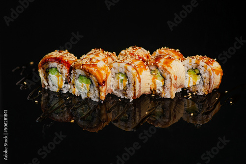 Sushi roll on black glossy background.
