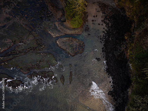 Shooting from a drone. Water surface and stones. River, sea, ocean. Dark tones. Dust. Abstraction. There are no people in the photo. Nature, ecology, geology, environmental protection.