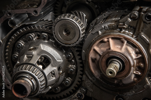 Gears, cogs and bearing of a dissasembled gearbox in a garage ready for repair