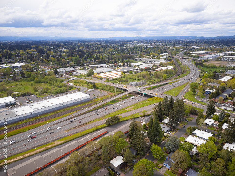 Shooting from a drone. Large highway, traffic near the green town. A mountain range is visible in the distance. Cloudy sky. Ecology, environmental protection, construction, planning, infrastructure. Shooting from a drone. Large highway, traffic near the green town. A mountain range is visible in the distance. Cloudy sky. Ecology, environmental protection, construction, planning, infrastructure.