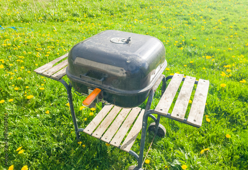 Beautiful metal barbecue grill closed on the lawn on a summer day. Black weber for outdoor cooking