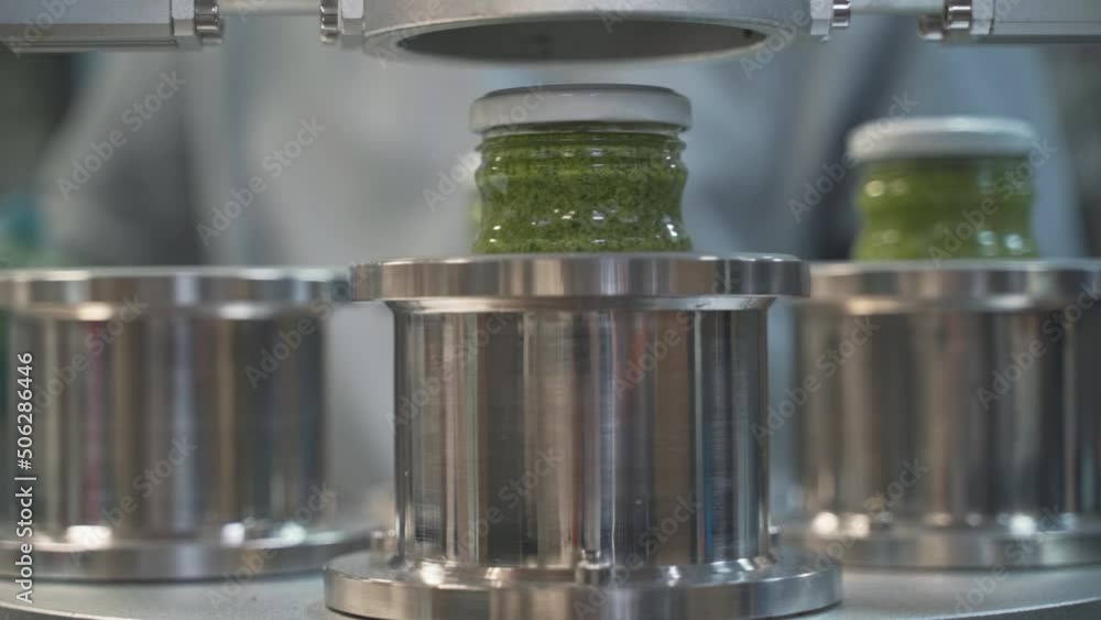 close up on Pesto sauce Industrial process. vacuum sealing machine for canned food. production of Pesto sauce. Vacuum Seamer for Cylindrical Cans of Rotary Type. close up on Pesto sauce Industrial process. vacuum sealing machine for canned food. production of Pesto sauce. Vacuum Seamer for Cylindrical Cans of Rotary Type.
