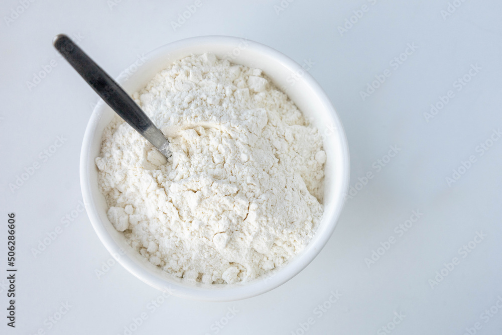 flour in a white bowl on a white background