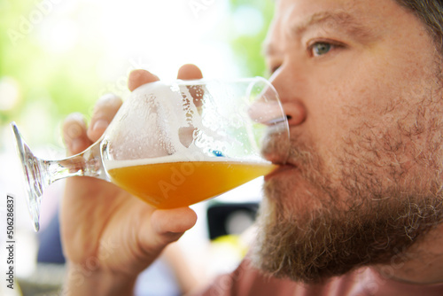 nordic bearded man drinking beer in a glass outdoors in summertime