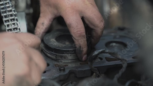 Mechanic installing piston with new rings inside the cylinder. Car engine overhaul