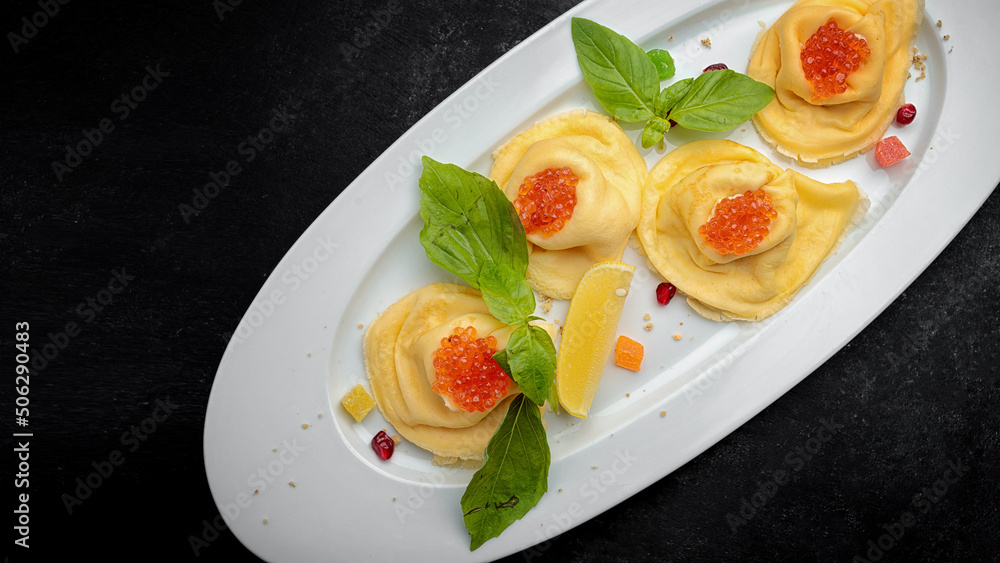 Pancakes with red caviar, basil, dark background Pancakes with red caviar, basil, dark background